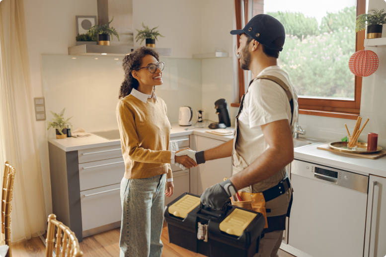 A woman and man shaking hands in the kitchen.