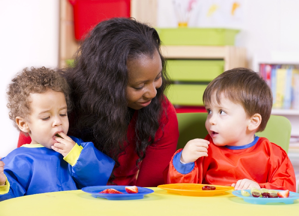 A woman and two children eating food at the table.